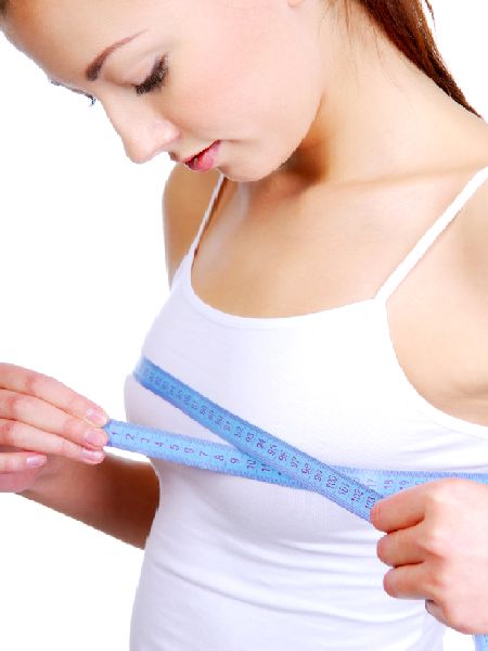 Young adult girl measuring her perfect breast - isolated on a white background
