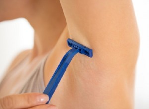 Closeup on young woman shaving armpit