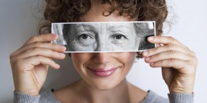 Woman with photo of elderly woman's eyes on hers'